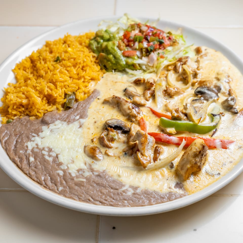 Mexican combination plate with yellow rice, refried beans, creamy mushroom-and-pepper chicken, guacamole, and pico de gallo.