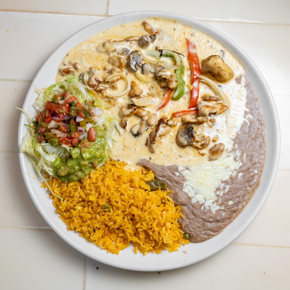 Mexican-style plate with creamy chicken, mushrooms and peppers, rice, refried beans, guacamole, and pico de gallo.