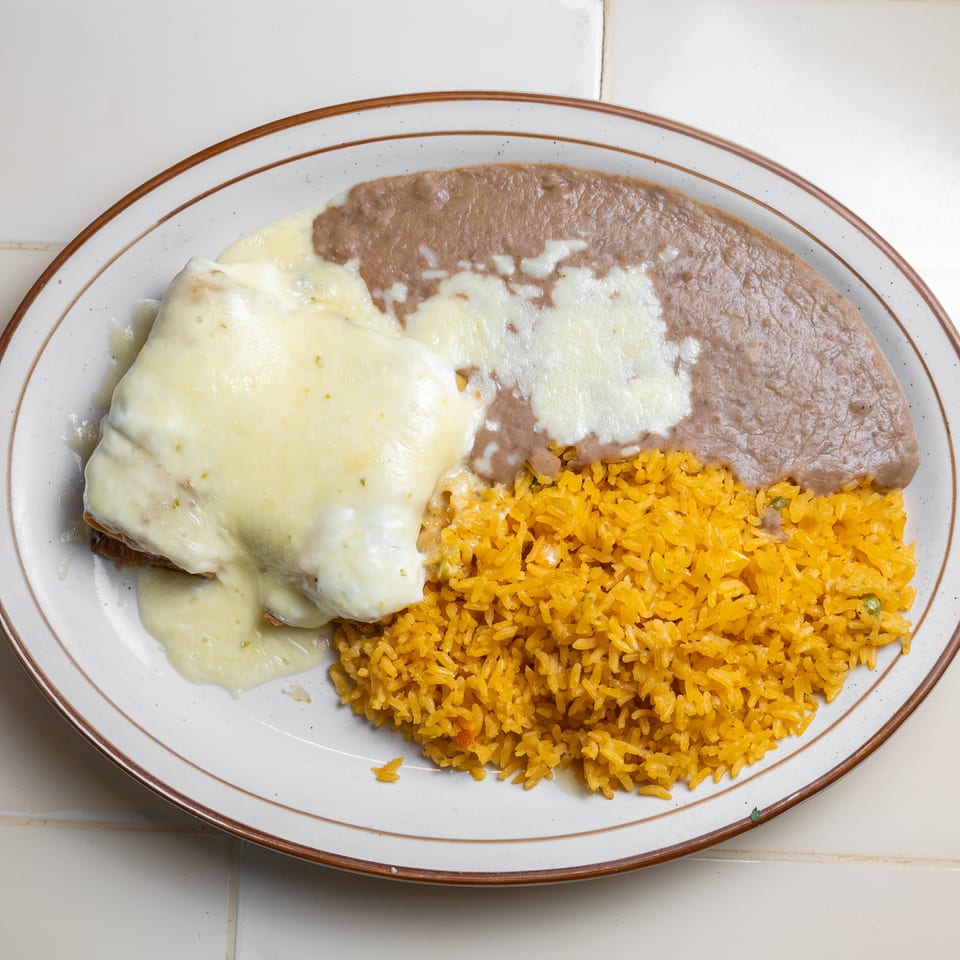 Plate of cheesy enchiladas served with refried beans and orange Mexican rice.